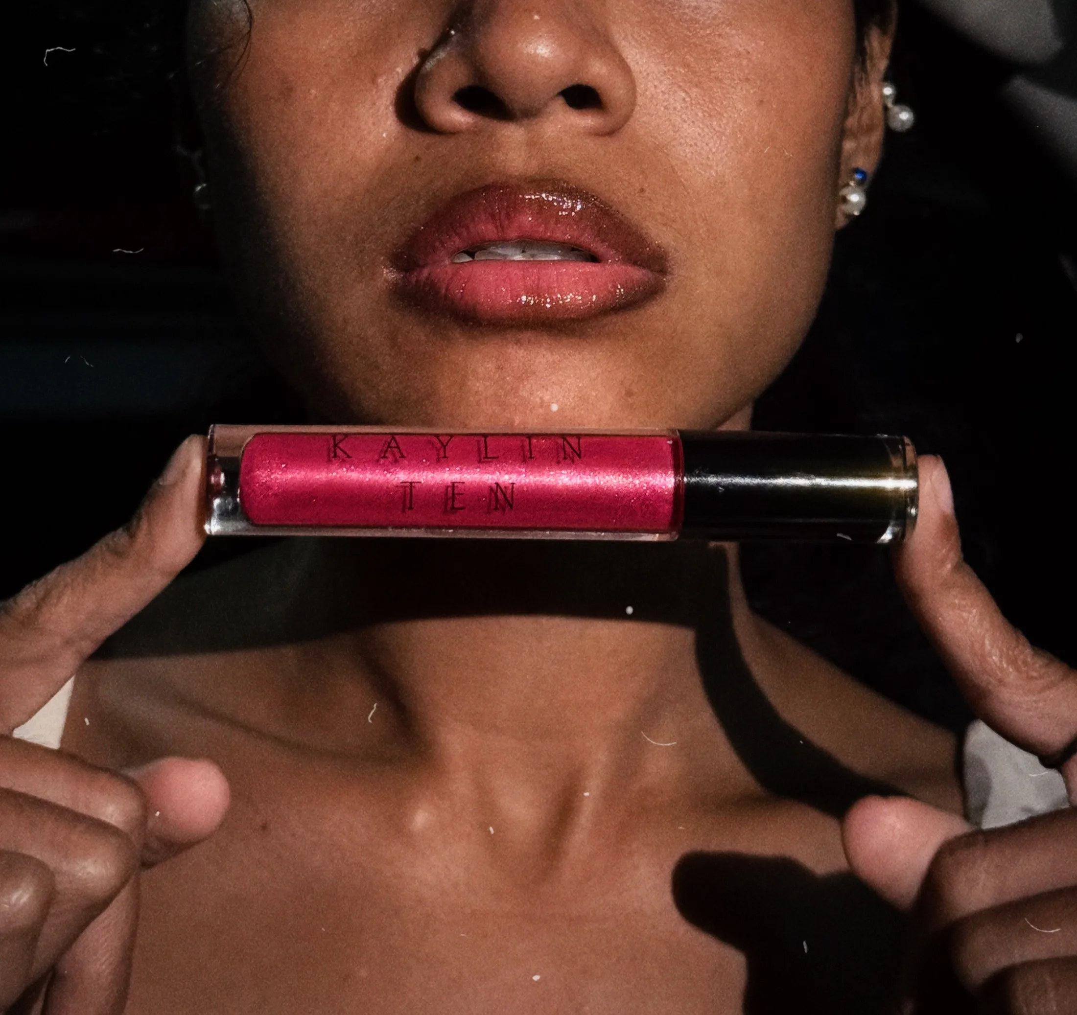 Close portrait with a bright pink lip gloss held below the face