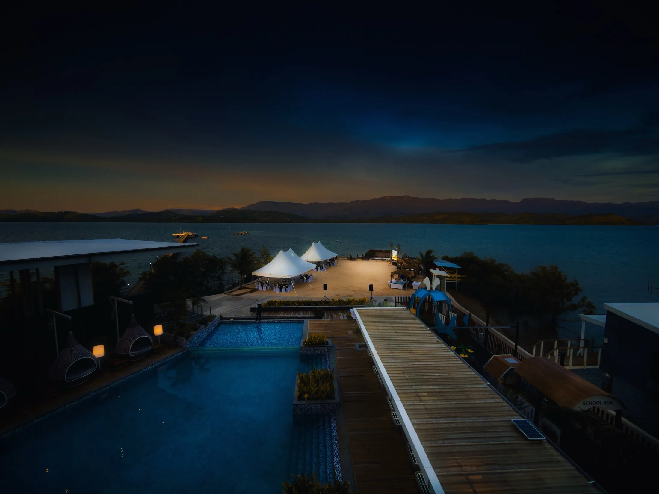 Waterfront property with a pool and outdoor event space at dusk