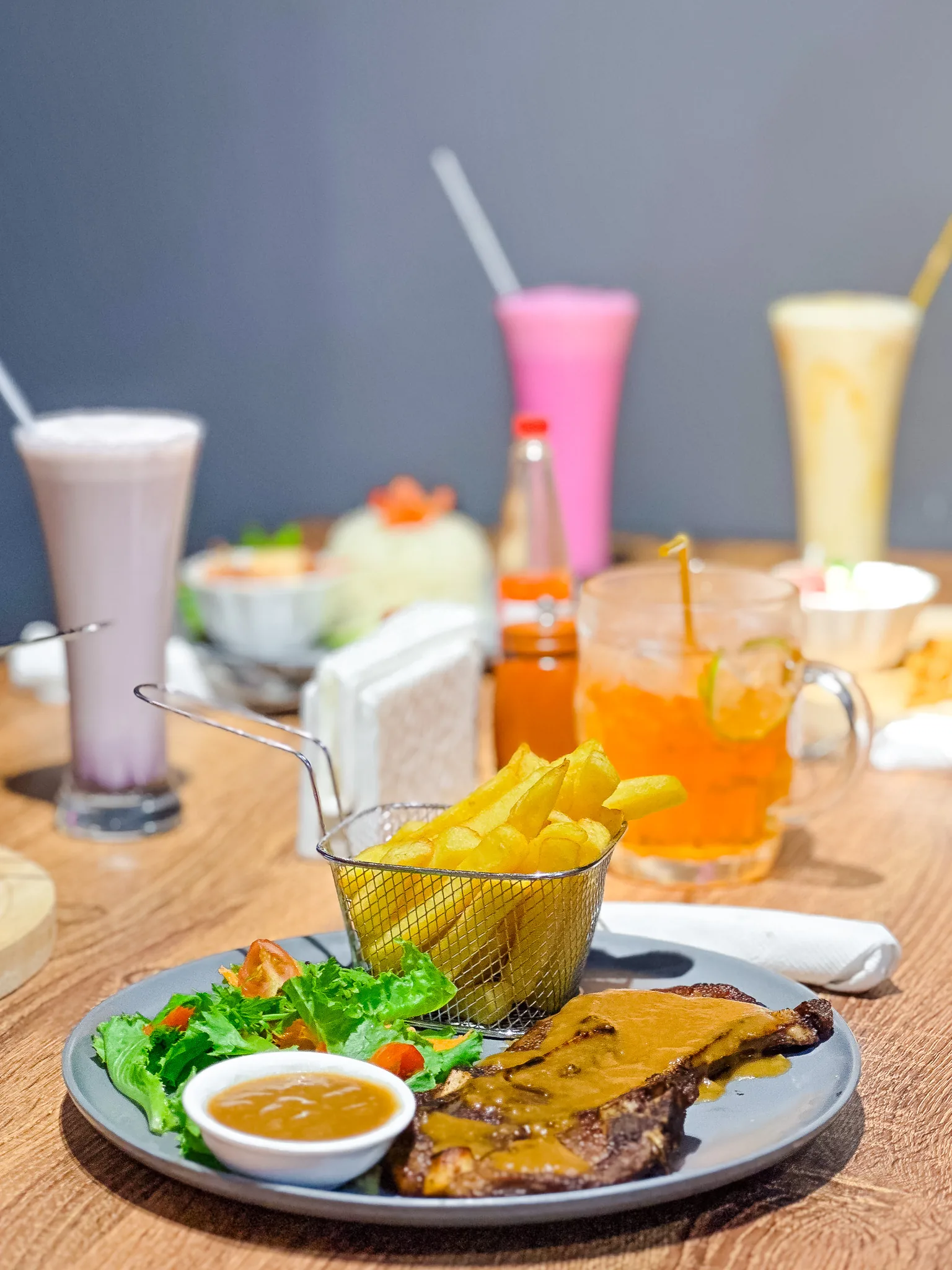 Steak, fries, salad and drinks on a dining table