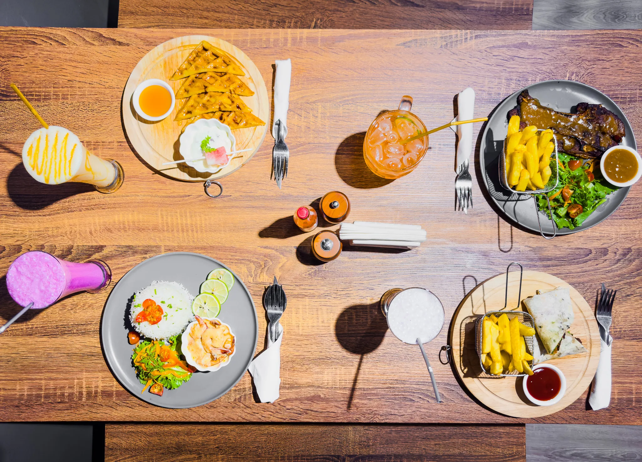 Several plated meals and drinks arranged across a table