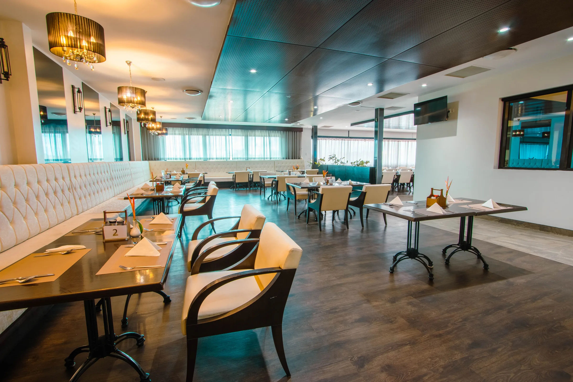 Restaurant seating and set tables beneath pendant lights