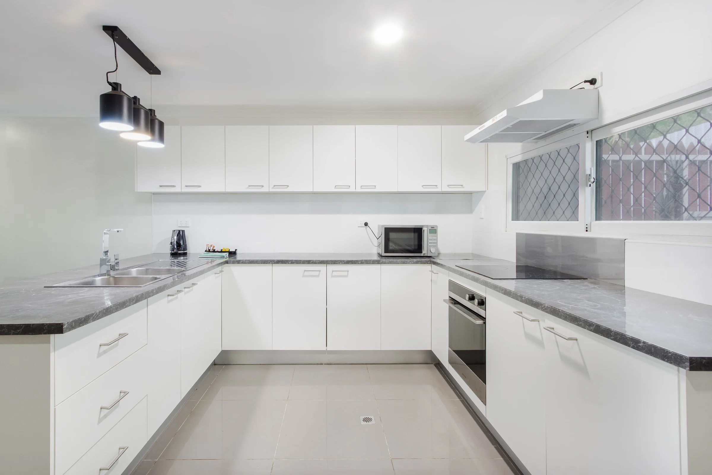 Bright kitchen with white cabinetry and dark worktops