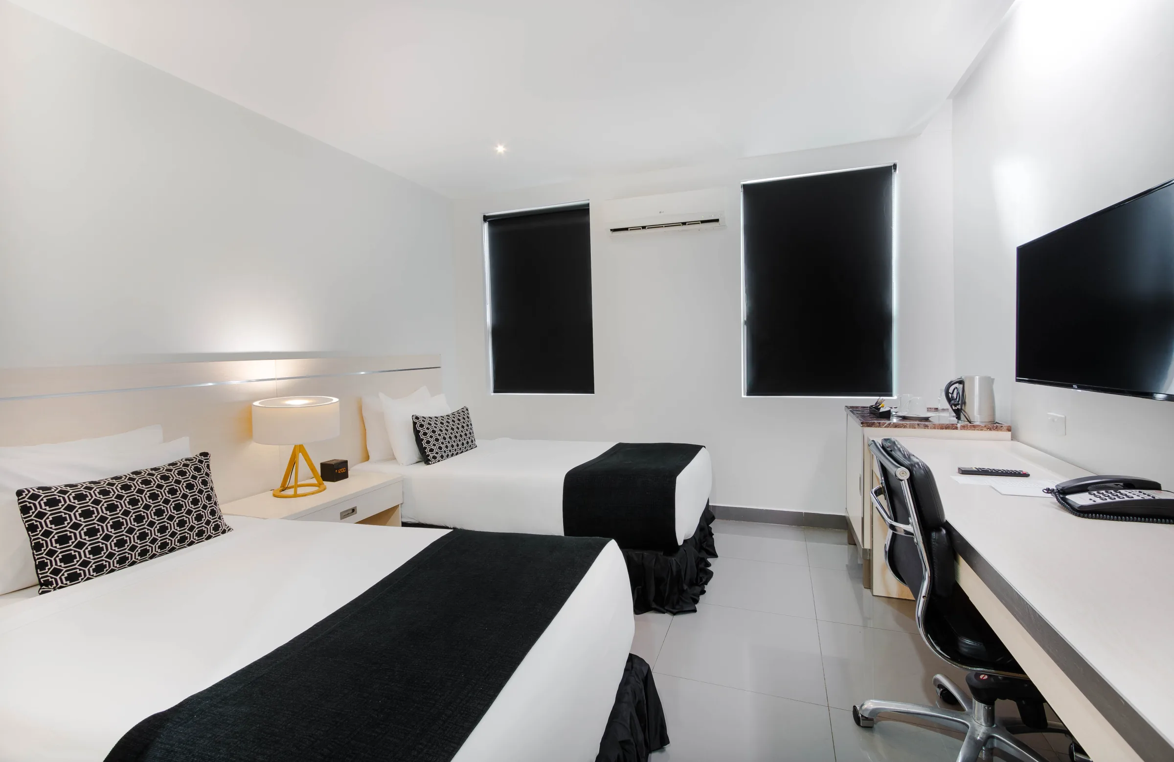 Two neatly made beds in a bright twin hotel room