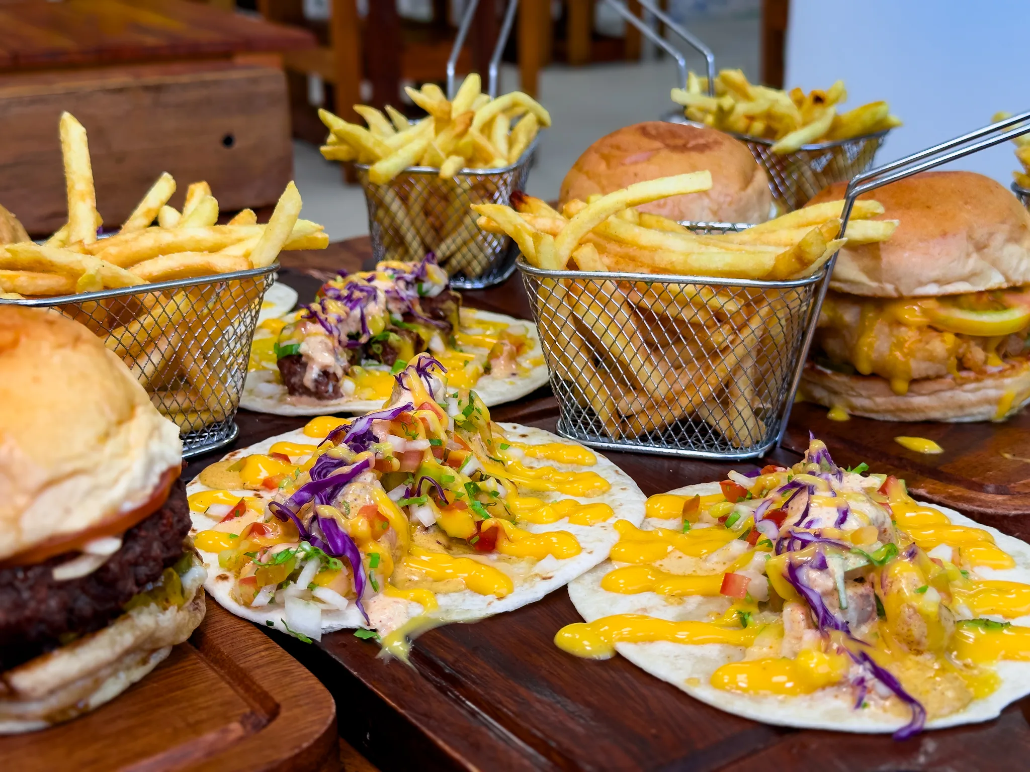 Burgers, tacos and fries laid out on wooden boards
